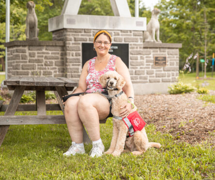 Woman sits next to standard poodle