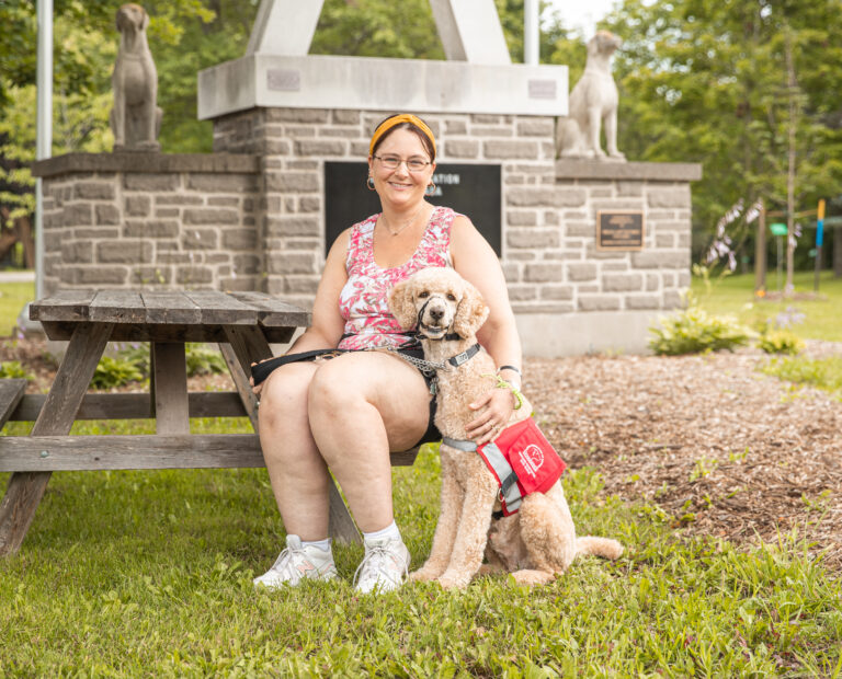 Woman sits next to standard poodle