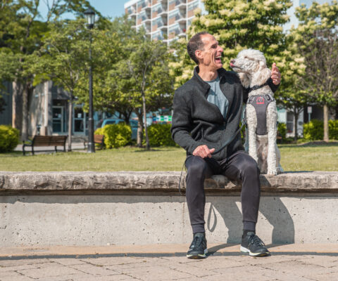 A man who is blind laughs as his Guide Dog kisses him