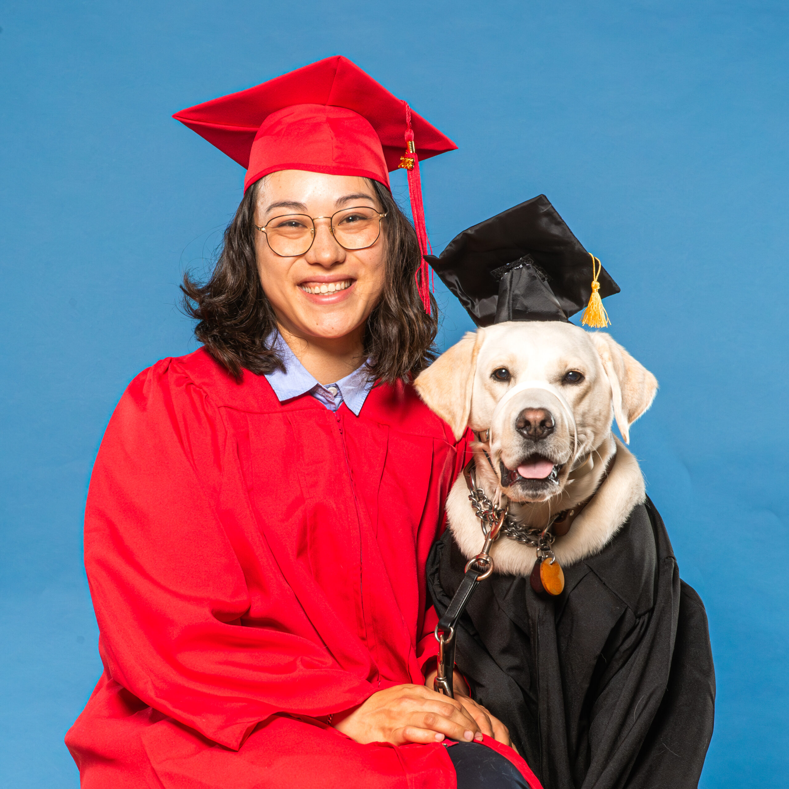 Graduate-Ellen-Vesper-3 women in graduation gown sits next to dog in graduation gown